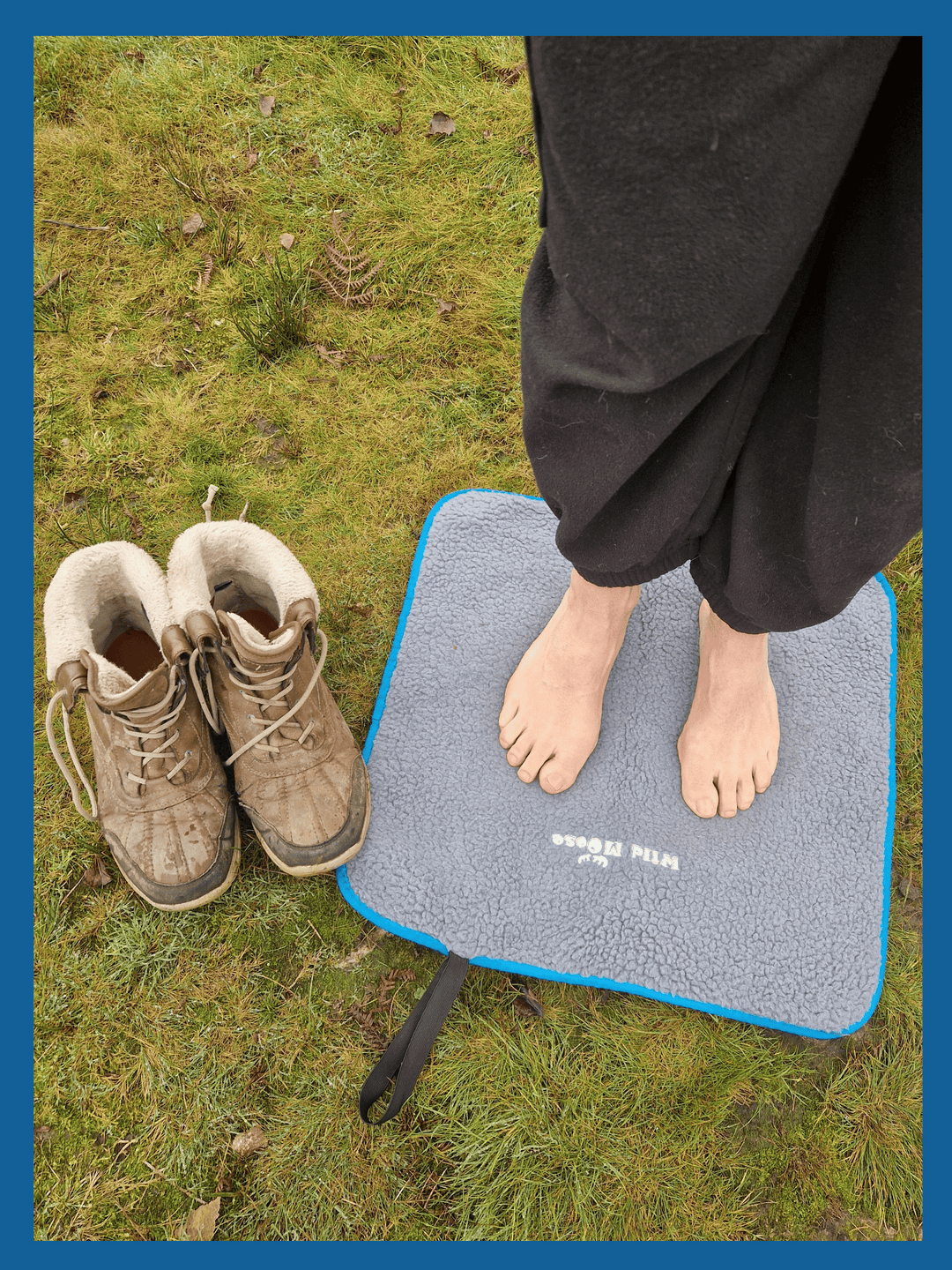 bare feet on a fleece lined changing mat on grass, with a pair of boots next to the mat