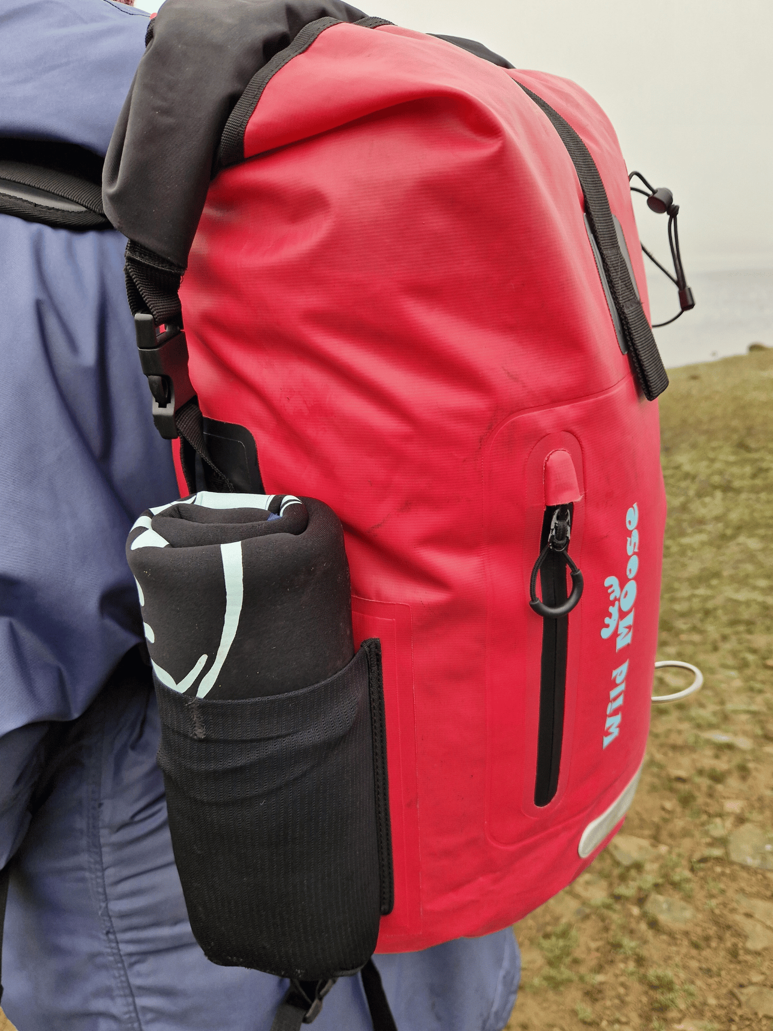 a rolled up changing mat in the stretchy side pocket of the pink Caribou backpack - neoprene side showing