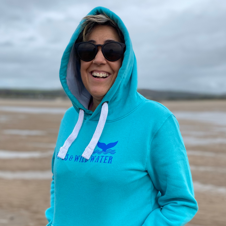 Claire from Waves and Wild Water loves her heavyweight hoodie in Lagoon! She's wearing it on the beach, with the contrast hood pulled up against the wind, and is probably wondering if it's too cold to go for a swim.