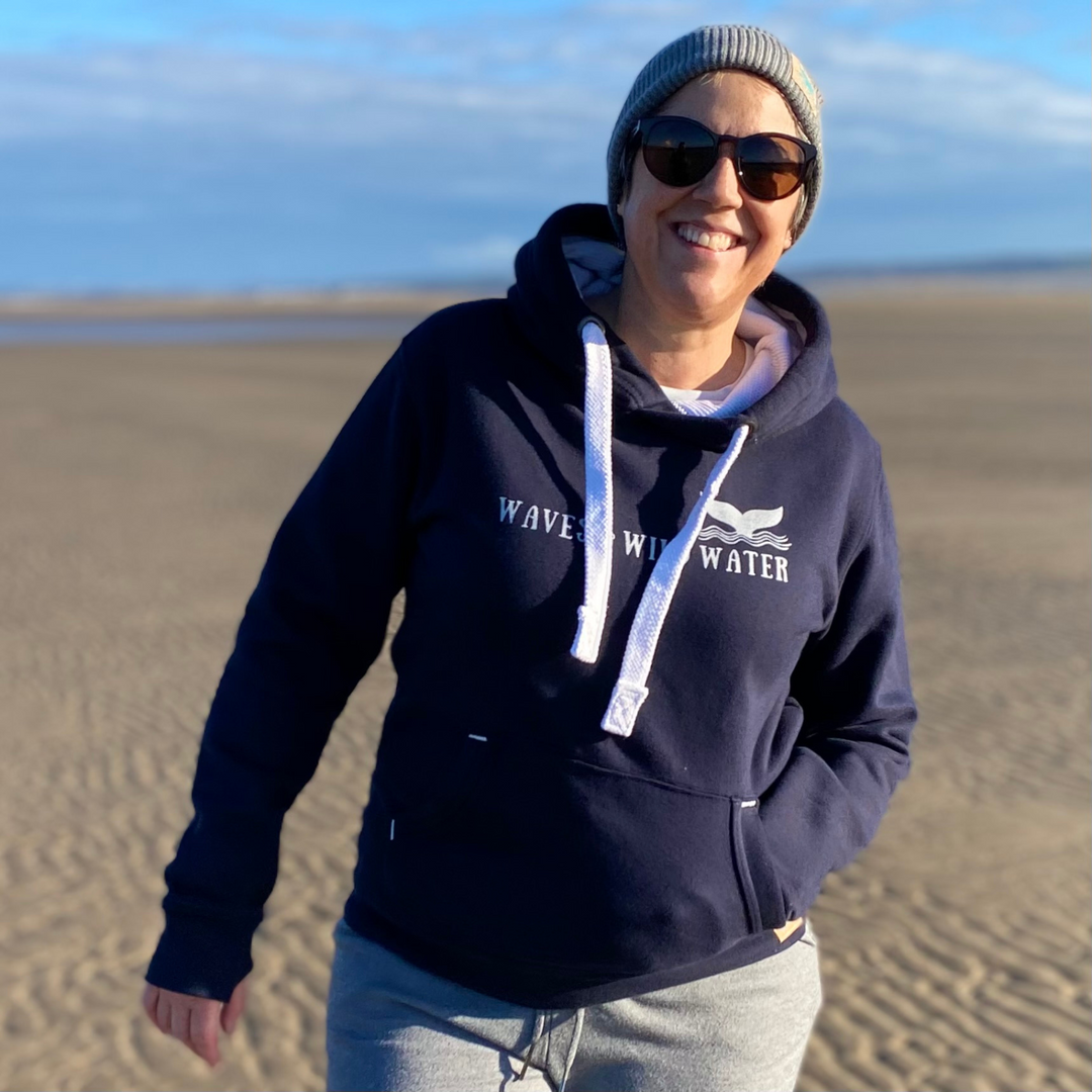 Waves and Wild Water owner, Claire, wears her navy blue hoodie with a frosty grey fisherman beanie. And although it's cold enough for a hoodie on the beach, the sun is out, so shades are on!